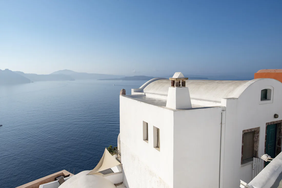 Στενό πέτρινο δρομάκι με λευκά σπίτια και φούξια λουλούδια