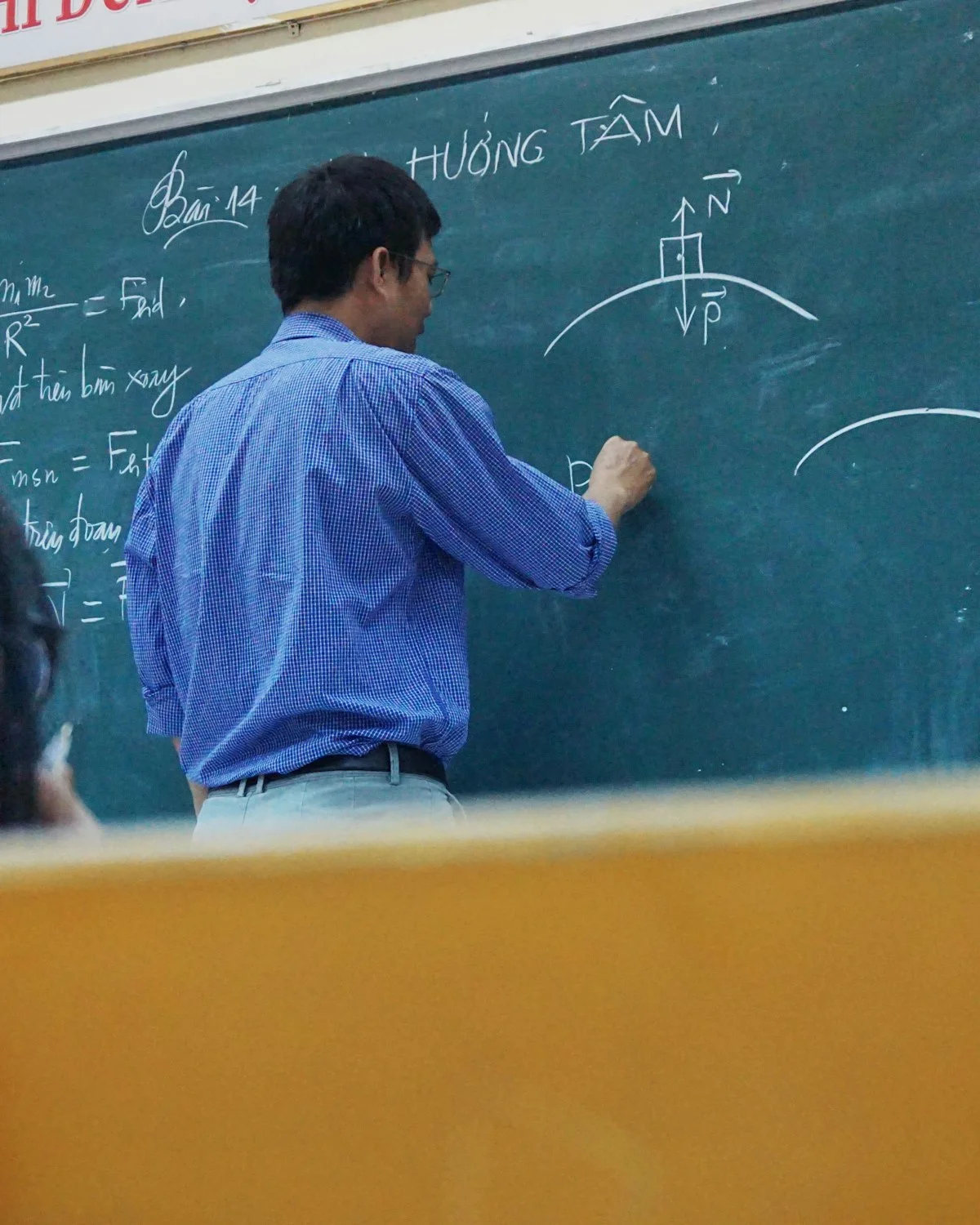 Καθηγητής γράφει εξισώσεις φυσικής σε πίνακα